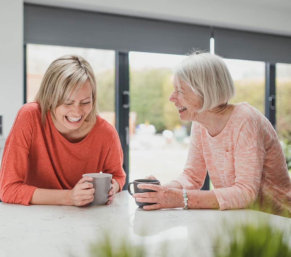 Adult daughter laughing at the counter with her mother