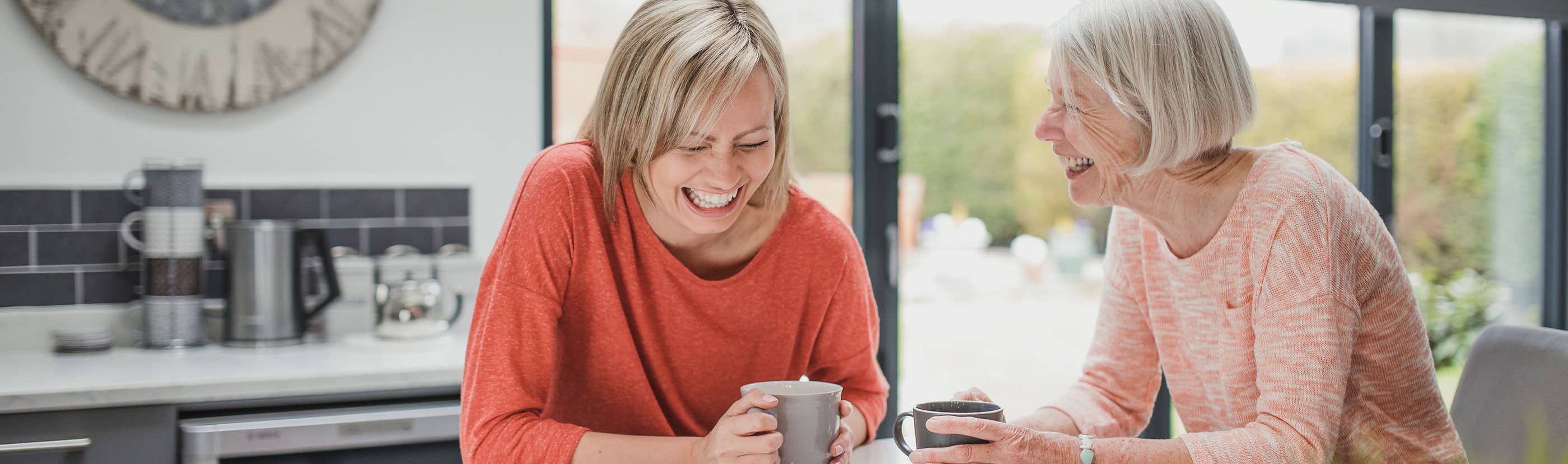 Adult daughter and mom laugh over coffee