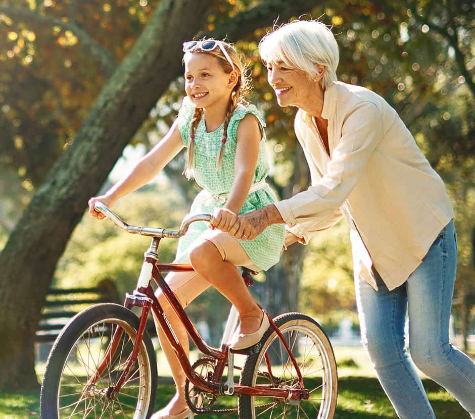 Grandma helping granddaughter learn to bike