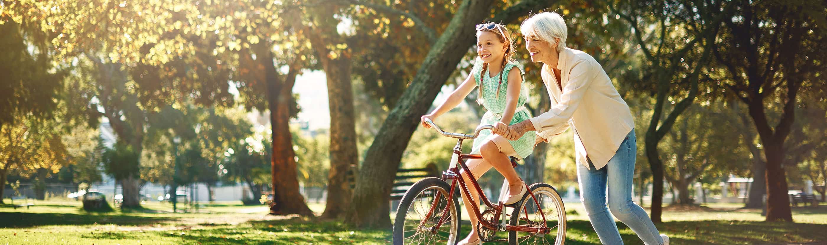 Grandma helping granddaughter learn to bike