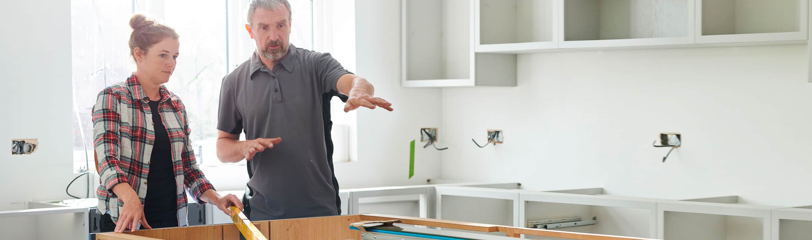 Woman and man with level and unfinished kitchen island