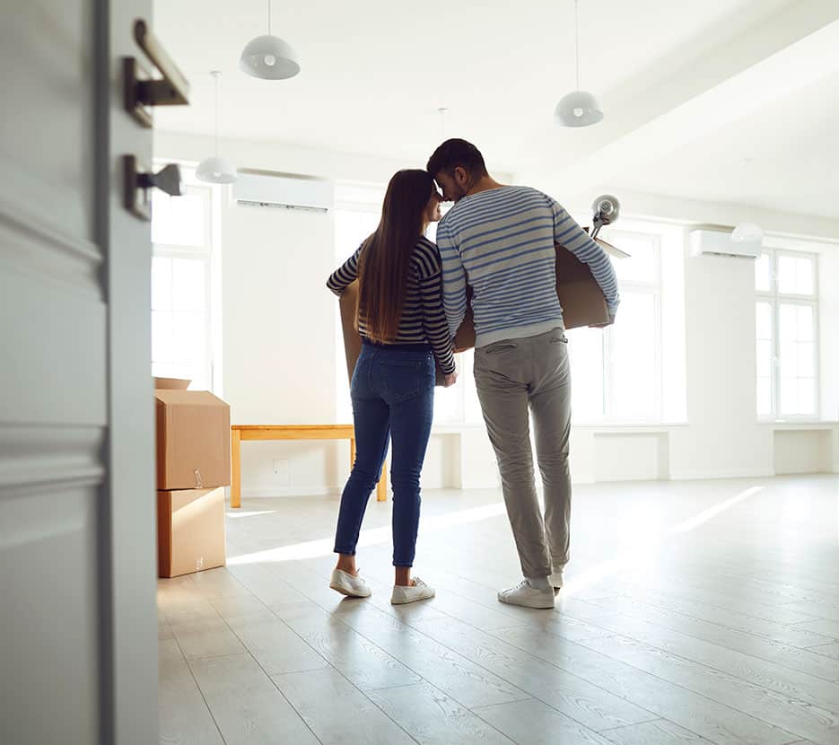 Young couple entering new home with moving boxes